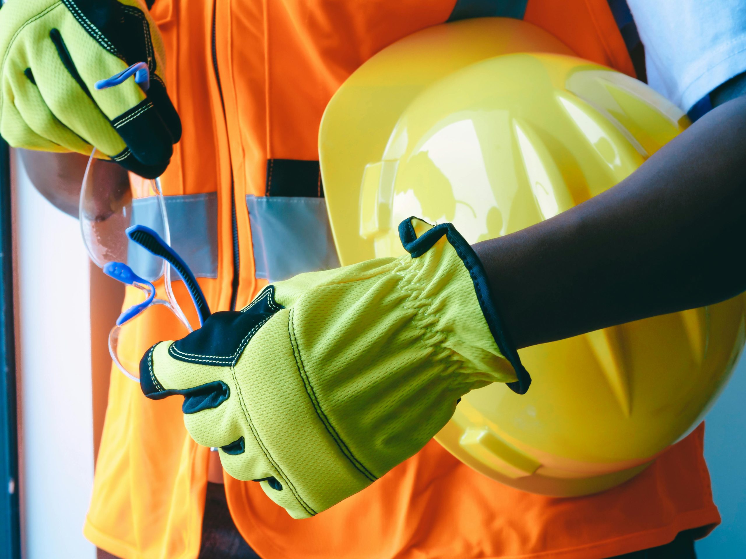 Construction worker holding a helmet and safety glasses in her hands.