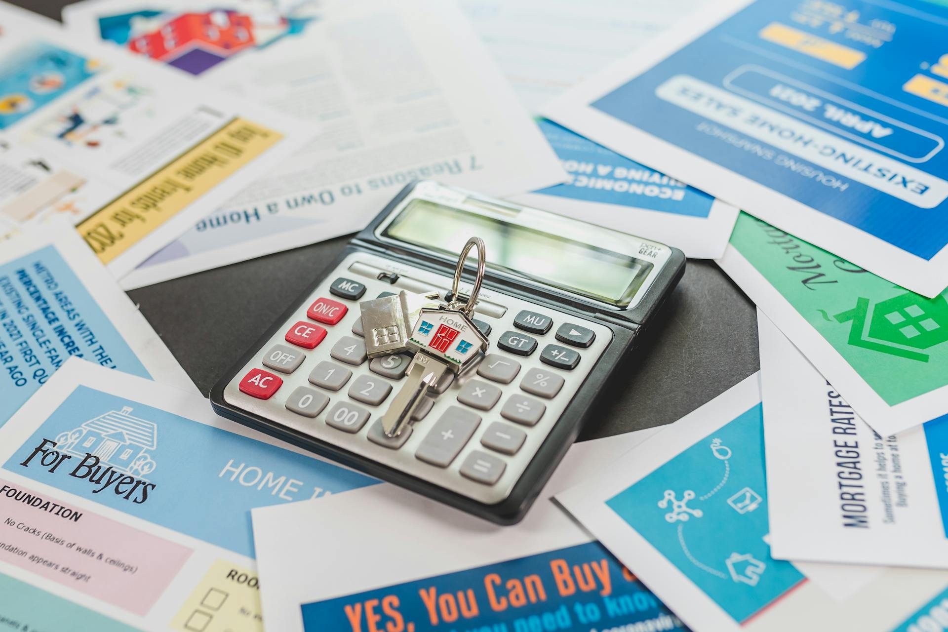 Calculator with a house key and papers for calculating a mortgage.