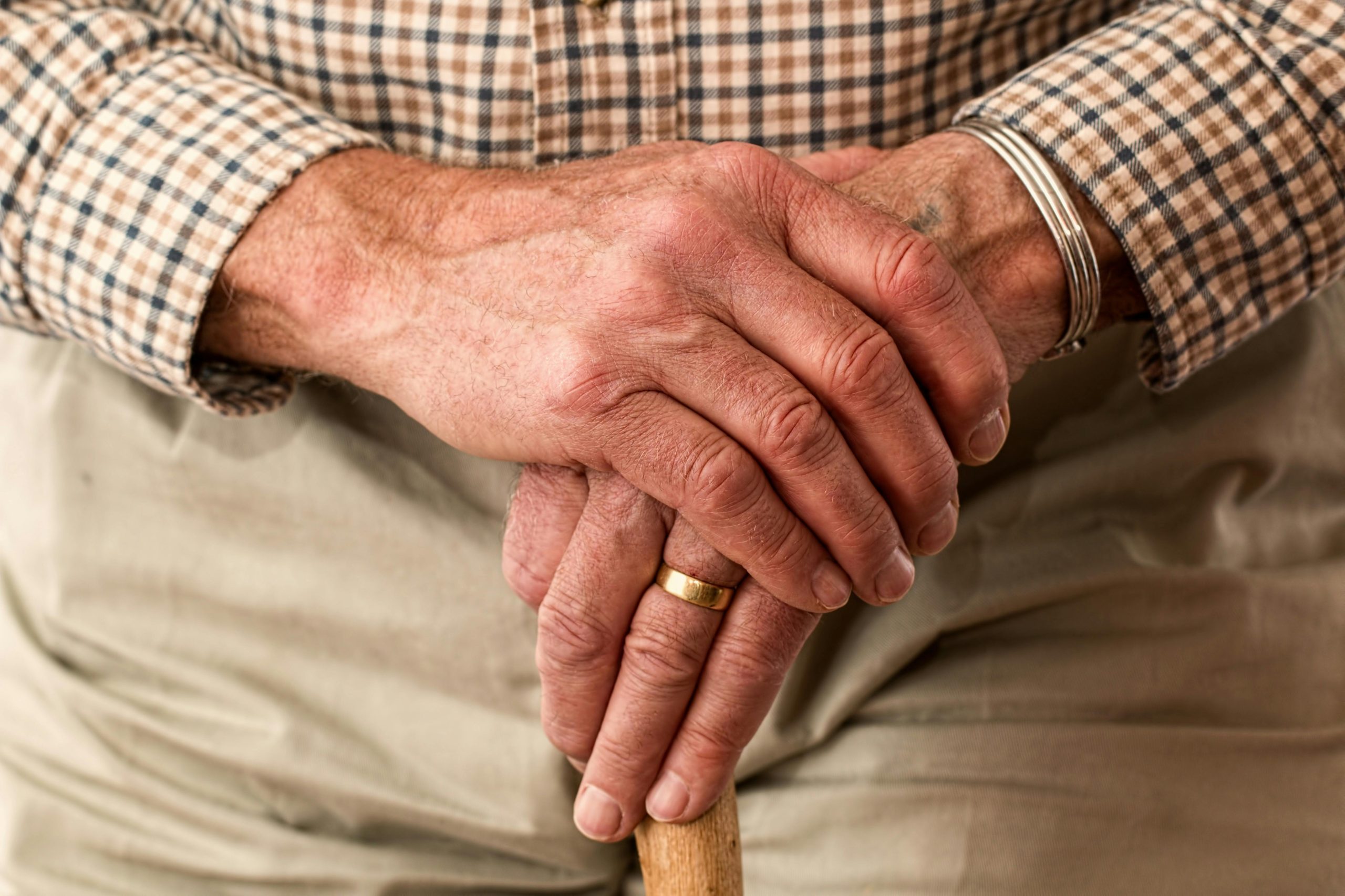 Gros plan sur les mains d'un homme âgé tenant sa canne.