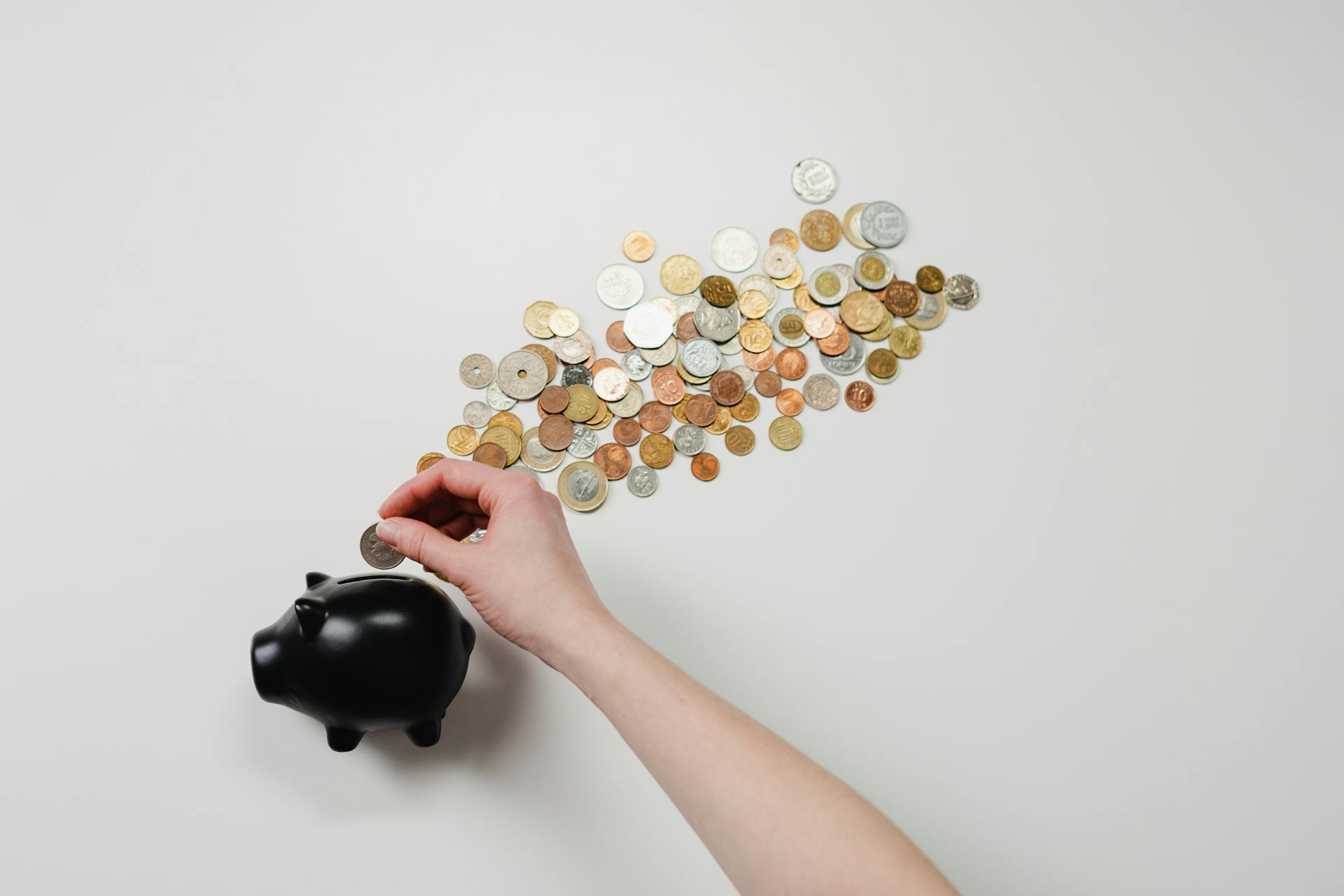 A person puts coins into a piggy bank.