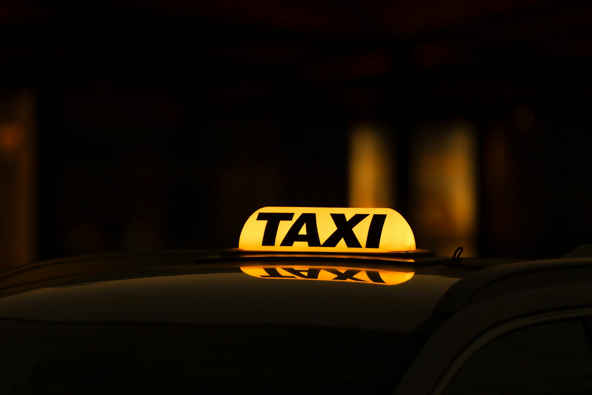 Taxi with a yellow illuminated sign reading "TAXI".